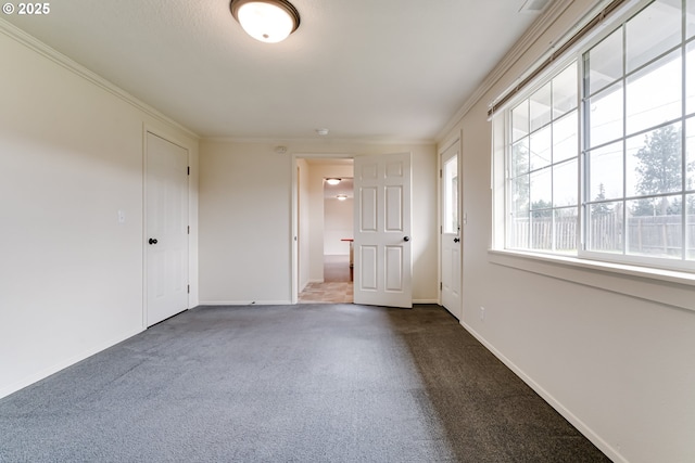 empty room with visible vents, ornamental molding, baseboards, and dark colored carpet