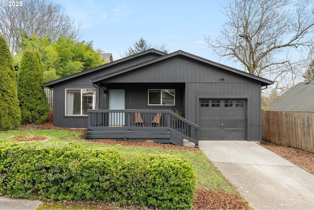 view of front of property with a garage, covered porch, concrete driveway, and fence