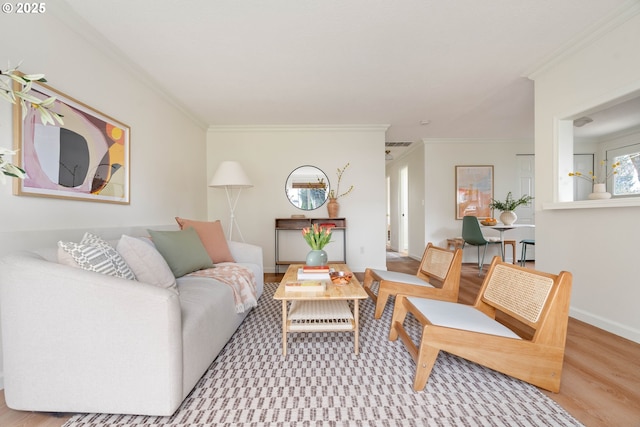 living area featuring baseboards, wood finished floors, and ornamental molding