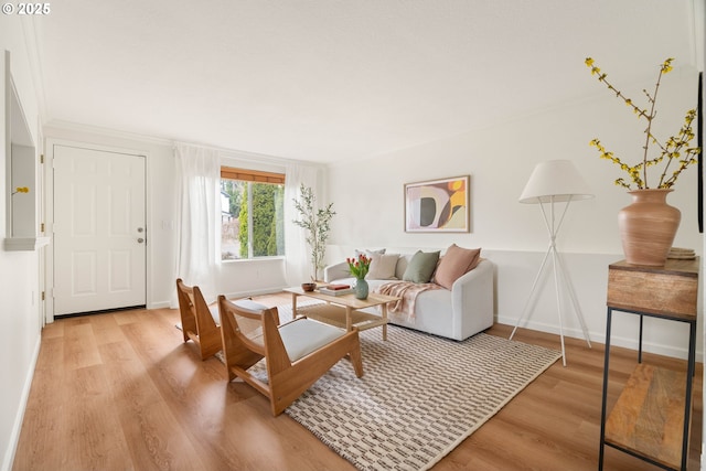 living area with crown molding, baseboards, and wood finished floors