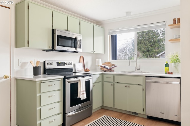 kitchen with a sink, appliances with stainless steel finishes, green cabinets, and light countertops