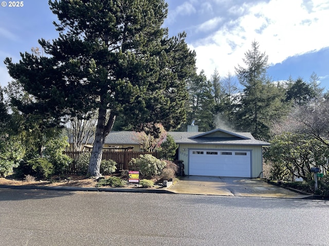 view of front of home featuring a garage, a chimney, driveway, and fence