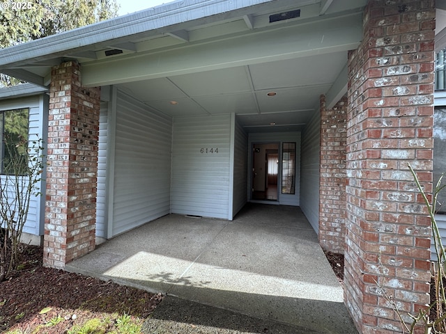 view of exterior entry featuring brick siding