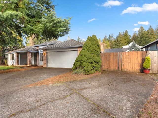 view of property exterior with brick siding, driveway, an attached garage, and fence