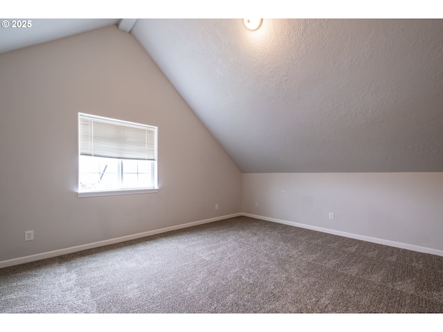 additional living space featuring carpet, vaulted ceiling with beams, a textured ceiling, and baseboards