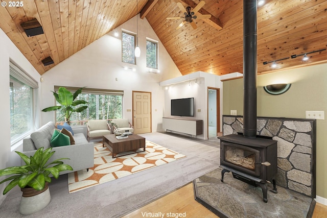 living room with wood ceiling, light wood-type flooring, a wood stove, ceiling fan, and beam ceiling