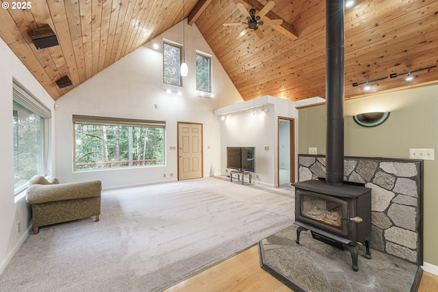 carpeted living room with wood ceiling, ceiling fan, beam ceiling, high vaulted ceiling, and a wood stove