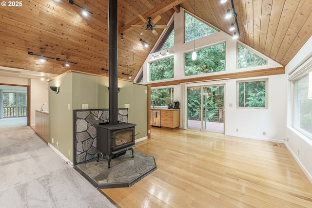 living room with wooden ceiling, light hardwood / wood-style floors, high vaulted ceiling, and a wood stove