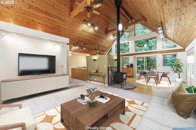 living room with wood ceiling, ceiling fan, high vaulted ceiling, and a wood stove