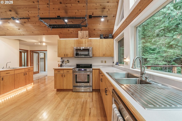 kitchen with pendant lighting, appliances with stainless steel finishes, sink, and light hardwood / wood-style flooring