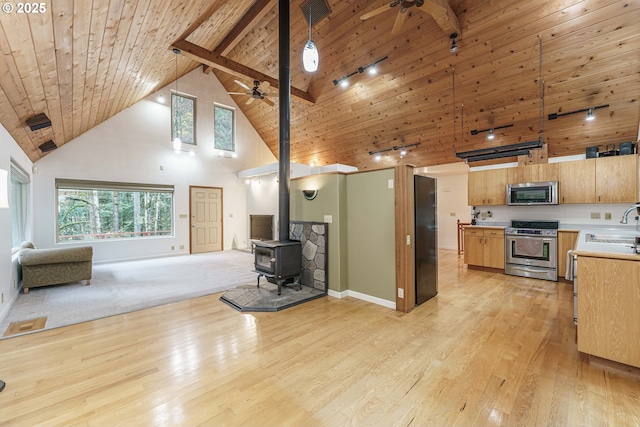 kitchen with ceiling fan, high vaulted ceiling, stainless steel appliances, wooden ceiling, and a wood stove