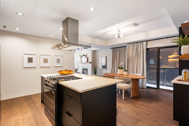 kitchen with island exhaust hood, a kitchen island, double oven range, and hardwood / wood-style flooring