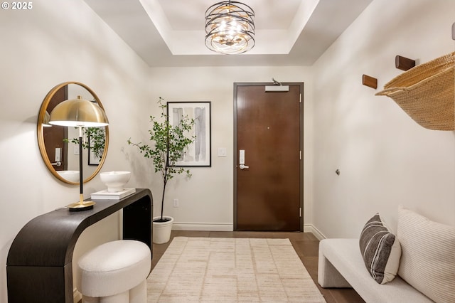 tiled foyer featuring a tray ceiling and a chandelier