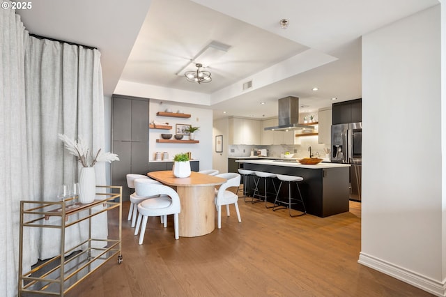 dining area with light hardwood / wood-style flooring and a raised ceiling