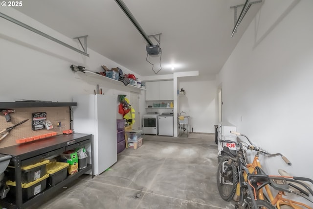 garage featuring washer and dryer, sink, white fridge, and a garage door opener