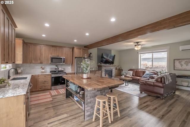 kitchen with a center island, wood counters, stainless steel appliances, beamed ceiling, and sink