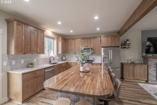 kitchen featuring stainless steel appliances, decorative backsplash, light hardwood / wood-style flooring, and light stone countertops