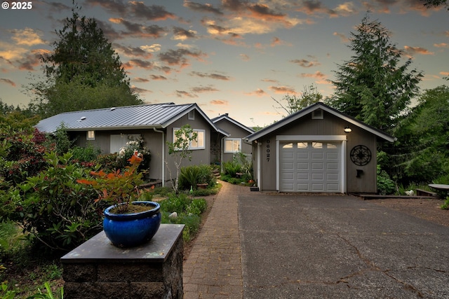 6027 View Loop, Florence, OR 97439 - view of front of house with a standing seam roof, a garage, a metal roof, and asphalt driveway