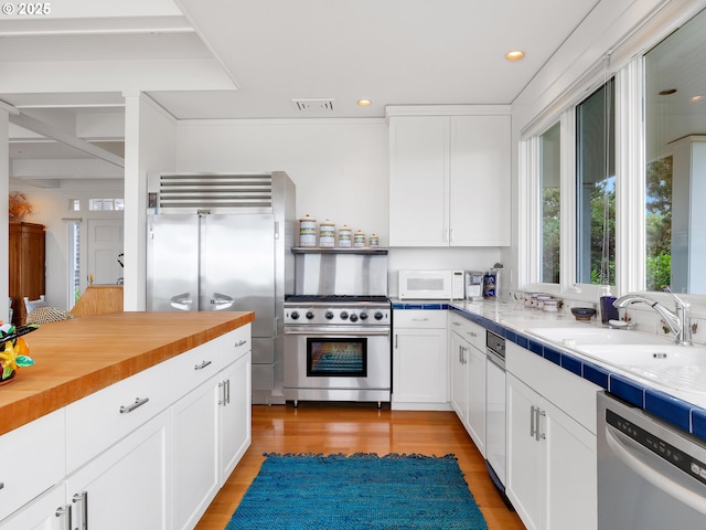 766 Neacoxie Blvd, Gearhart, OR 97138 - kitchen with high quality appliances, white cabinets, butcher block countertops, light wood finished floors, and a sink