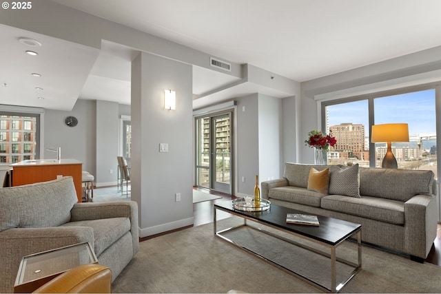 living room featuring a healthy amount of sunlight, sink, and light hardwood / wood-style flooring