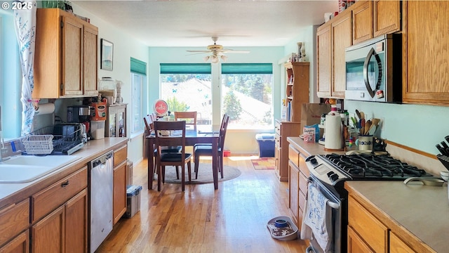 1234 E Fourth Ave, Sutherlin, OR 97479 - kitchen featuring appliances with stainless steel finishes, light wood-style flooring, light countertops, ceiling fan, and brown cabinetry