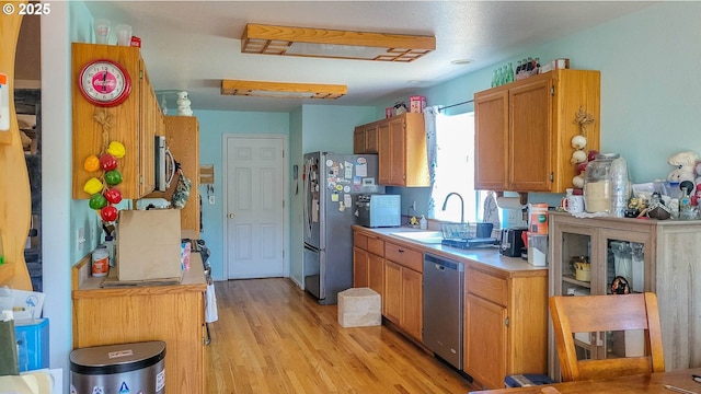 1234 E Fourth Ave, Sutherlin, OR 97479 - kitchen with a sink, light countertops, stainless steel appliances, light wood-style floors, and brown cabinets