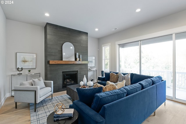 living room with a large fireplace and light wood-type flooring