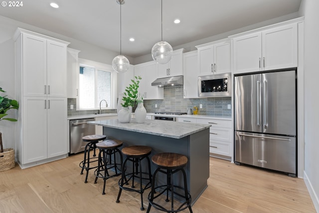 kitchen featuring a kitchen island, white cabinetry, appliances with stainless steel finishes, and decorative light fixtures