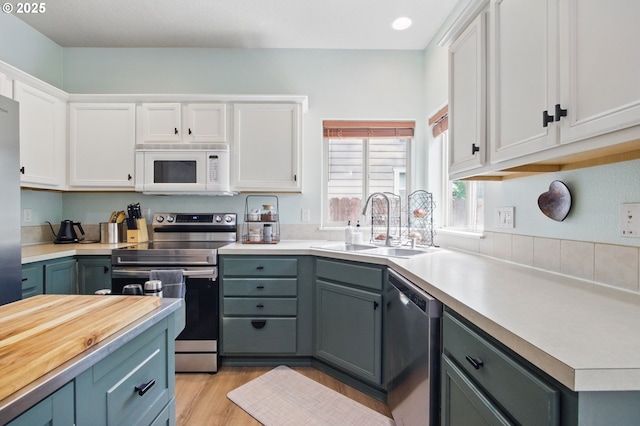 1146 SE Millright Ave, Mcminnville, OR 97128 - kitchen with appliances with stainless steel finishes, white cabinets, a sink, light wood-type flooring, and gray cabinetry