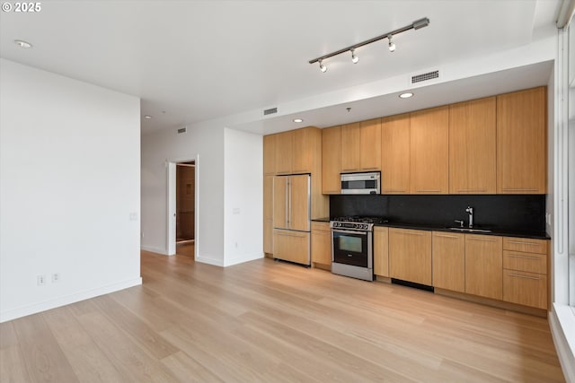 949 NW Overton St Unit 1007, Portland, OR 97209 - kitchen featuring appliances with stainless steel finishes, dark countertops, light wood-style flooring, a sink, and recessed lighting