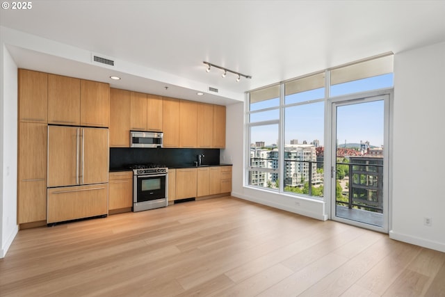 949 NW Overton St Unit 1007, Portland, OR 97209 - kitchen with appliances with stainless steel finishes, light wood-style flooring, a sink, dark countertops, and baseboards