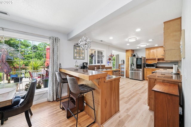 35111 Jefferson Ln, Astoria, OR 97103 - kitchen with stainless steel appliances, a peninsula, light wood finished floors, a kitchen bar, and recessed lighting