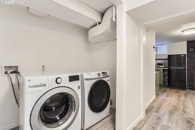 clothes washing area featuring washer and clothes dryer and light hardwood / wood-style floors