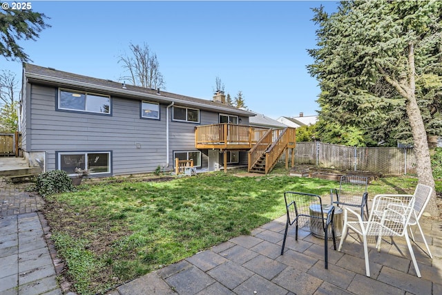 rear view of house with a wooden deck, a yard, and a patio area