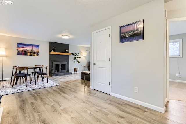 dining space with a brick fireplace and light hardwood / wood-style floors