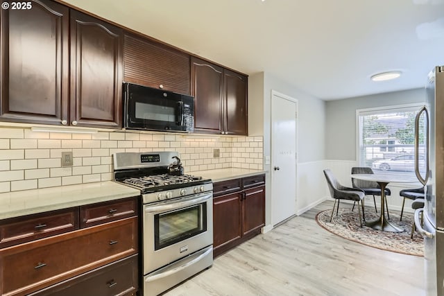 kitchen with tasteful backsplash, appliances with stainless steel finishes, dark brown cabinets, and light hardwood / wood-style floors