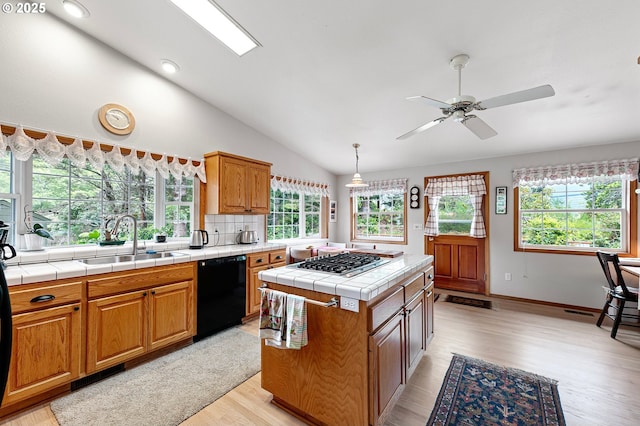 20 Wild Winds St, Florence, OR 97439 - kitchen with dishwasher, stainless steel gas cooktop, tile countertops, light wood-style floors, and vaulted ceiling