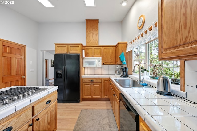 20 Wild Winds St, Florence, OR 97439 - kitchen with black appliances, tile counters, light wood finished floors, and decorative backsplash