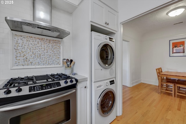 1534 NE 26th Ave Unit 8, Portland, OR 97232 - clothes washing area featuring stacked washing machine and dryer, light wood finished floors, and baseboards