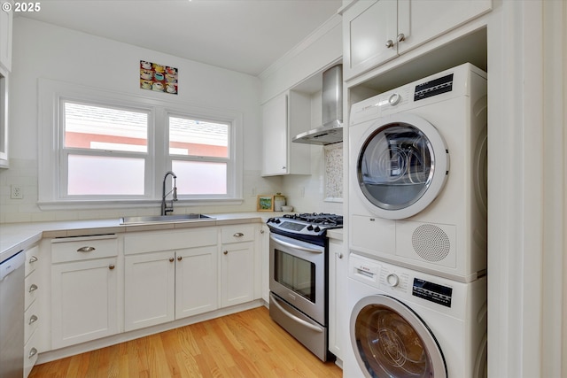 1534 NE 26th Ave Unit 8, Portland, OR 97232 - kitchen featuring stainless steel gas range oven, wall chimney exhaust hood, stacked washer / drying machine, a sink, and light countertops