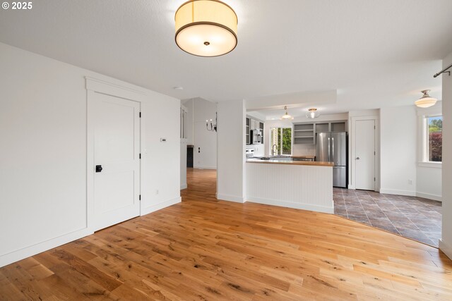 unfurnished living room featuring baseboards and light wood-style flooring