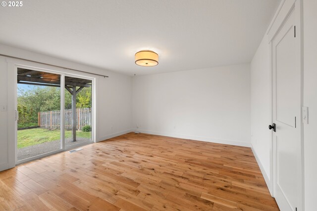 empty room featuring light wood-style floors, baseboards, and visible vents