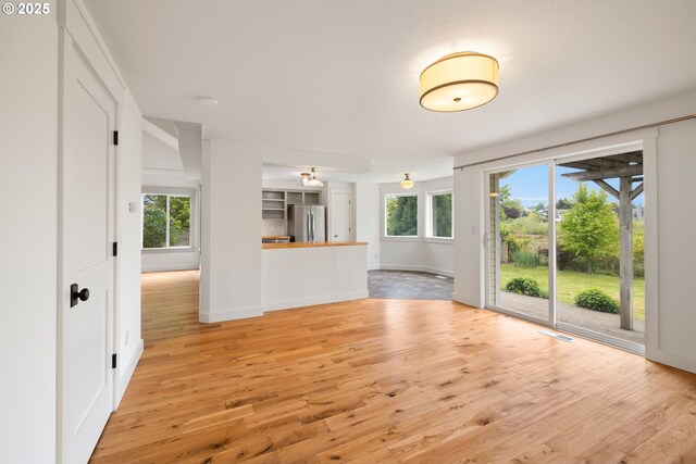 unfurnished living room featuring baseboards, light wood-style flooring, and visible vents
