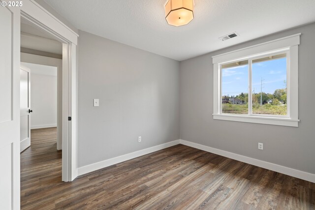 spare room featuring baseboards, visible vents, and wood finished floors