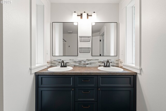 full bath featuring a sink, backsplash, and double vanity