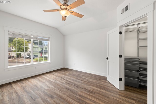 unfurnished bedroom featuring visible vents, vaulted ceiling, wood finished floors, baseboards, and a closet