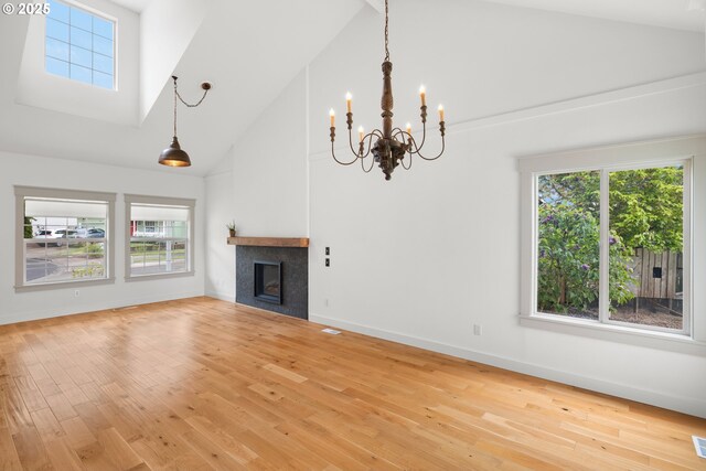 unfurnished living room featuring high vaulted ceiling, an inviting chandelier, and plenty of natural light
