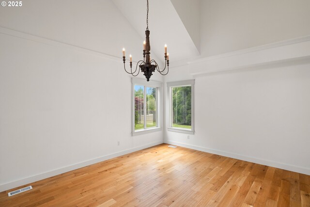 unfurnished room featuring visible vents, high vaulted ceiling, baseboards, light wood finished floors, and a chandelier