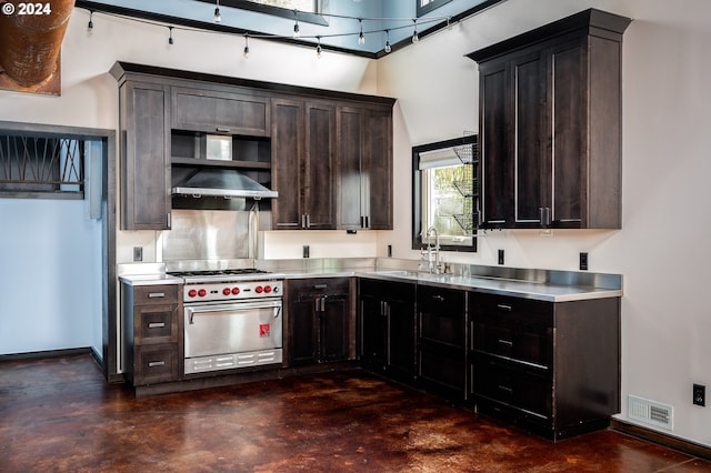 kitchen featuring dark brown cabinets, premium range, stainless steel counters, and sink