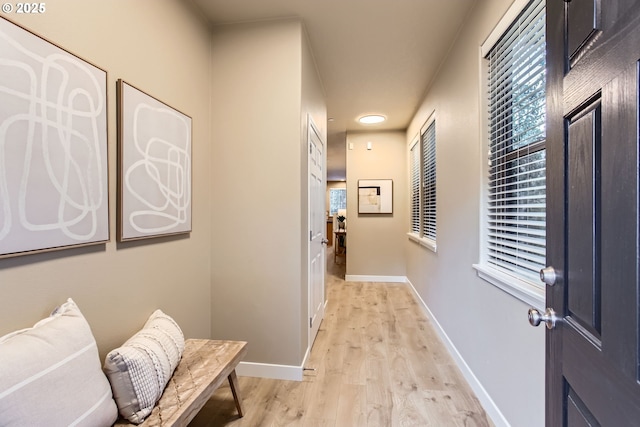 hall with light wood-style floors and baseboards